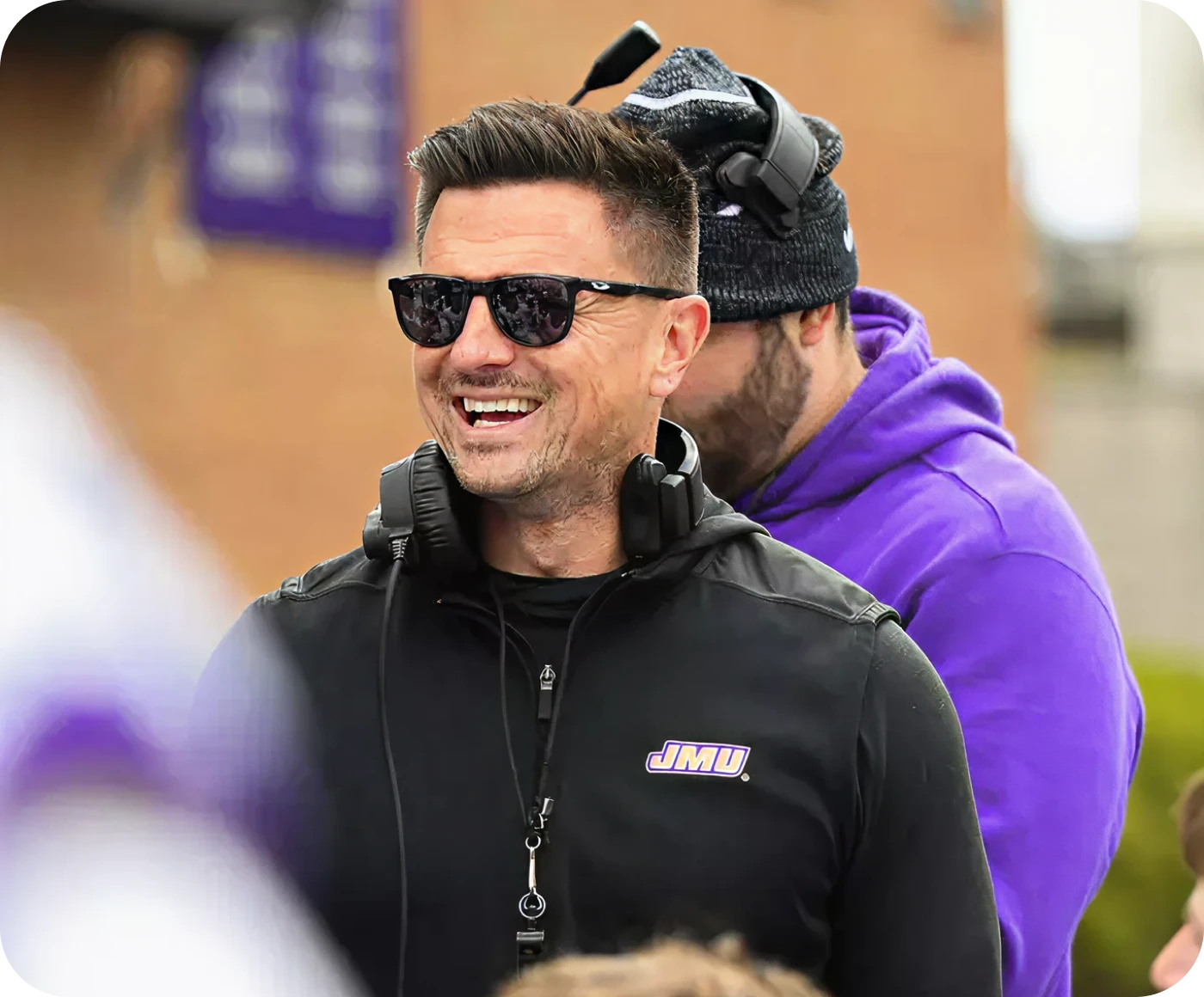 JMU football alumni coach smiling during a Dukes practice session