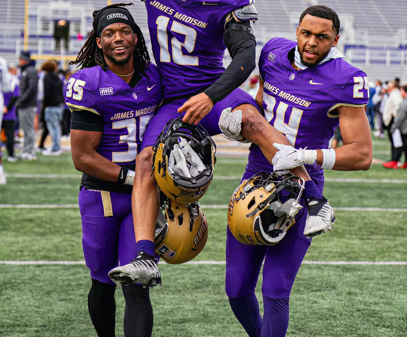 JMU football alumni players celebrating victory and milestone achievements on the field
