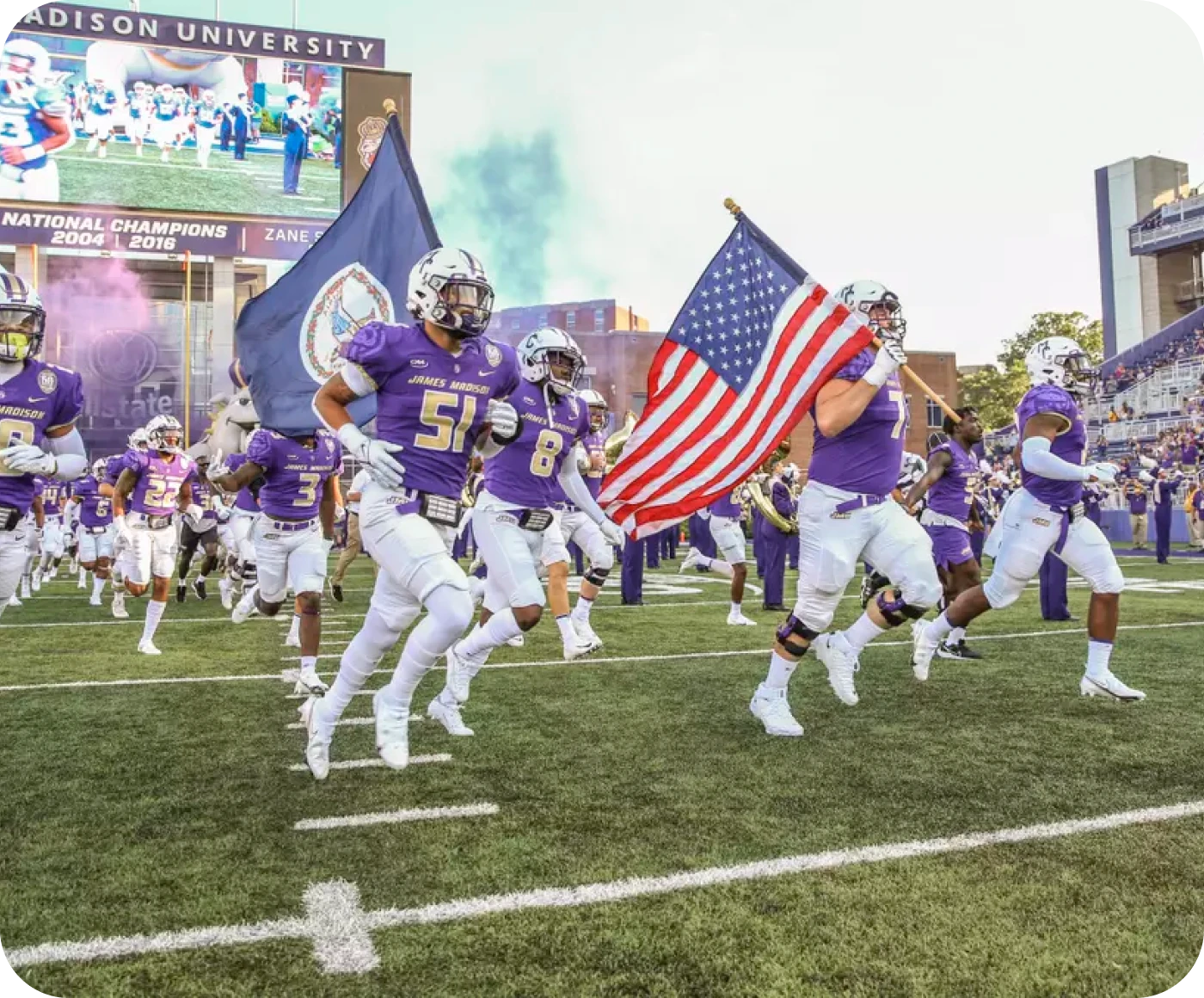 JMU football players running onto the field carrying American and Virginia flags on game day